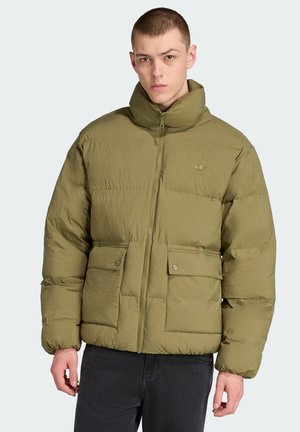 Chaqueta acolchada en verde oliva con cuello alto, cierre de cremallera y dos bolsillos frontales con botones a presión. Textura suave, diseño ligero.