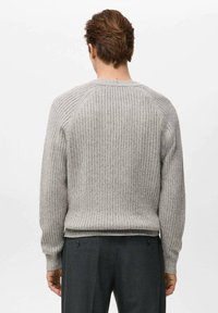 Szary dziany sweter o prążkowanej fakturze, z długimi rękawami i okrągłym dekoltem, widziany od tyłu. Wraz z ciemnymi spodniami.