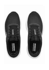 Černé sportovní boty s texturovaným síťovinovým svrškem, šněrováním a bílou podrážkou. Na stélce je značka "Skechers Air Cooled Goga Mat".