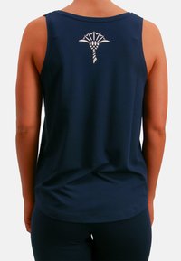 Laivastonsininen hihaton toppi, jossa on sileä pinta, valkoinen graafinen kuvio takana, pyöreä kaula-aukko ja rento istuvuus.