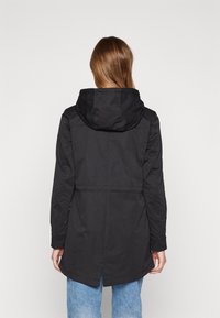 Svart lång jacka med huva, med en inringad midja och sidofickor. Slät tyg med en ren design.