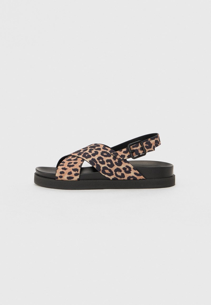 Sandália com padrão de leopardo, tiras cruzadas, detalhes em preto, fivela ajustável e sola plana. Material macio com superfície texturizada.