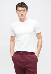 Λευκό κοντομάνικο μπλουζάκι με λαιμόκοψη, σε συνδυασμό με μπορντό φόρμες με κορδόνι στη μέση και πλαϊνές τσέπες.