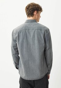 Herreskjorte med lange ærmer i falmet grå denim, knapper på kraven, buet kant og enkelt rygstykke med diskret syning.