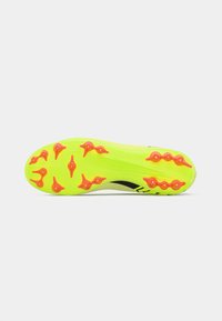 Suela de zapato deportivo amarillo con clavos naranjas, que presenta un patrón de agarre texturizado y un diseño de acento negro a lo largo del costado.