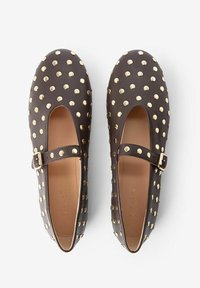 Chaussures en cuir marron avec un bout arrondi, dotées d'une sangle et d'accents en clous dorés sur le dessus. Texture lisse avec un système de fermeture à boucle sécurisée.