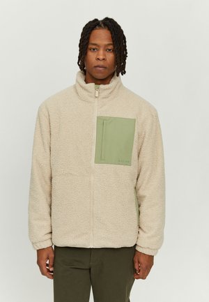 Beige Fleece-Jacke mit hohem Kragen, ausgestattet mit einer grünen Pattentasche und einem Frontreißverschluss. Weiche Textur und entspannter Schnitt.