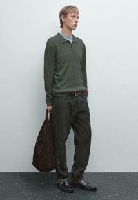 Grøn stribet langærmet polo med grå krave, mørkegrønne vide jeans, sorte loafers og en brun ruskinds tote bag.