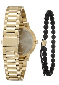 Reloj de metal dorado con pulsera de eslabones y esfera redonda junto a una pulsera de cuentas negras con cierre ajustable. Ambos artículos presentan un diseño elegante.