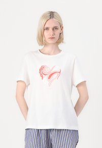 Vit bomull t-shirt med ett abstrakt hjärtdesign i rosa och rött, korta ärmar och avslappnad passform. Matchas med randsydda blå och vita shorts.