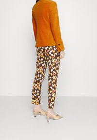 Orange kordfløjl blazer, mønstrede brune bukser med multicolor kyllinger, og beige hæle med spids tå og kitten heel.