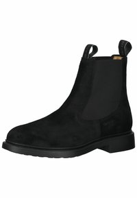 Bottines Chelsea en suede noir avec panneaux élastiques sur les côtés, deux tirants et une semelle en caoutchouc texturé. Dotées d'un bout arrondi et d'un design minimaliste.