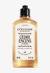 L'Occitane Cèdre Encens duschgel i en klar plastflaska. Har en svart pump-top, krämfärgad etikett med svart text och gyllene vätska. 250 ml.