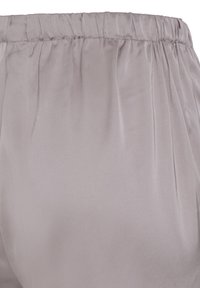 Tissu en satin gris clair avec taille élastique froncée, texture lisse et léger éclat, montrant une partie d'un vêtement.