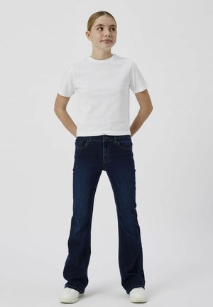 White short-sleeve T-shirt paired with dark blue flared jeans. The jeans feature front pockets and a button closure. White sneakers complete the look.