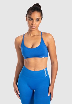 Blauwe sportbeha met een gladde textuur en dunne bandjes, gecombineerd met hoge blauwe leggings met een witte logo-accent.