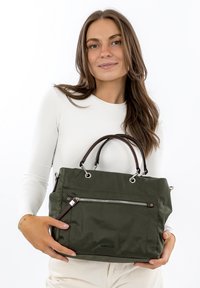 Zelená nylonová kabelka s hnědými koženými rukojeťmi, s přední kapsou na zip a stříbrnými kovovými detaily. Obdélníkový tvar, hladký povrch.