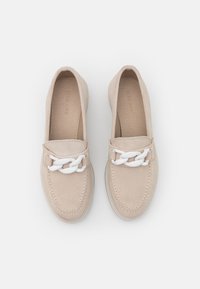 Mocassini in suede beige con una catena bianca sul davanti. Punta arrotondata, dettagli cuciti e rivestimento interno morbido.