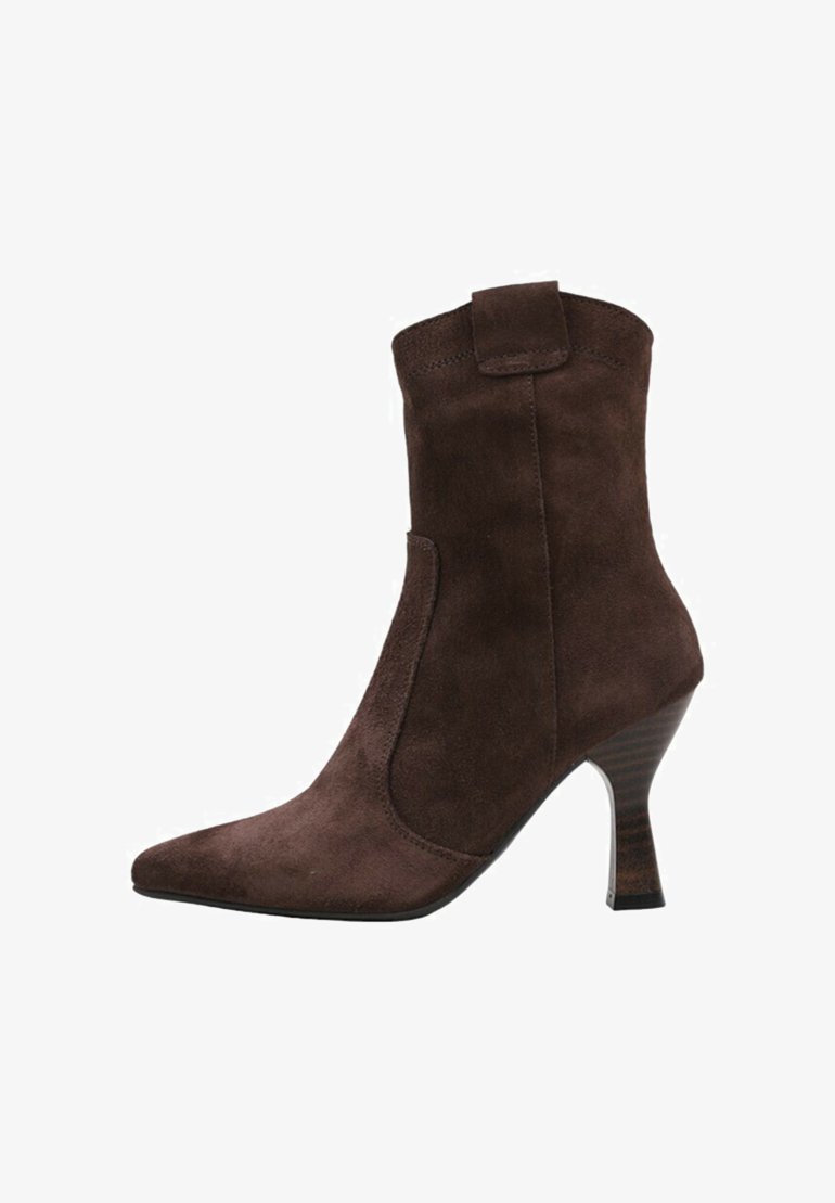 Botín de ante marrón hasta el tobillo con punta afilada y tacón de aguja. Presenta un panel elástico lateral y una lengüeta trasera para facilitar su puesta.