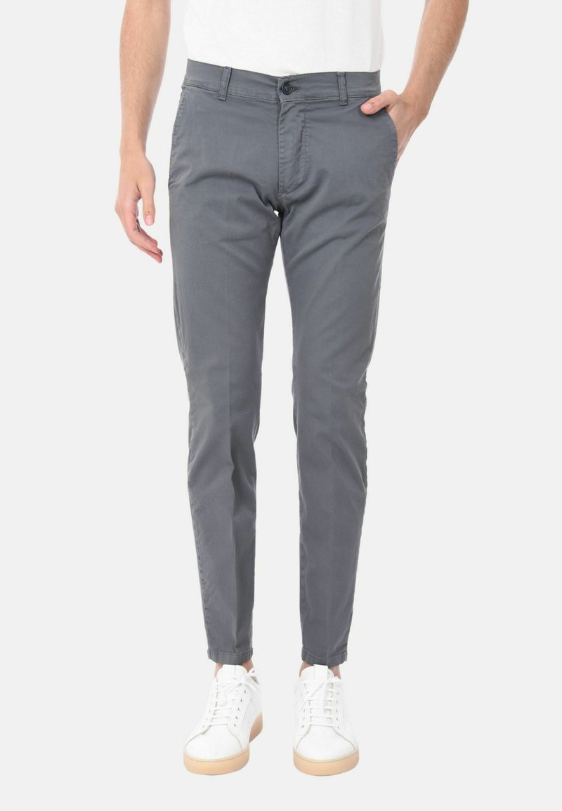 Pantaloni slim-fit grigi realizzati in un tessuto liscio, con tasche frontali e chiusura con bottone, abbinati a sneakers bianche.