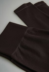 Geribbelde bruine legging met een gladde textuur en een brede tailleband. Heeft een aansluitend ontwerp dat taps toeloopt bij de enkels.