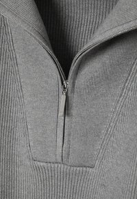 Gray knit pullover with a ribbed texture and a half-zip closure. It features a V-shaped collar and a smooth fabric inside.