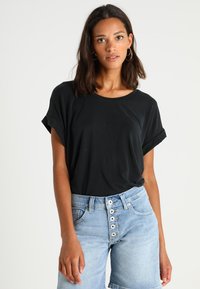 Black, short-sleeved top in soft fabric, paired with light blue high-waisted shorts featuring a button fly and a relaxed fit.