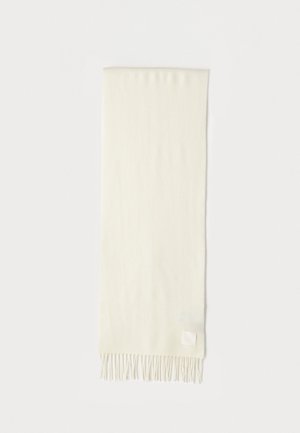 Sciarpa color crema chiara con una texture morbida, dettagli in frange alle estremità e un piccolo etichetta in tessuto nell'angolo inferiore.