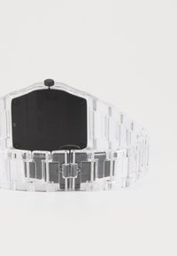Transparent plastic watch with a rectangular black face, linked strap, and a chunky, modern design. Features a textured surface and a crown.