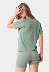 Světle zelené tričko s krátkým rukávem a volným střihem, doplněné o shodné kraťasy. Měkká tkanina, minimalistický design a žádné viditelné logo.