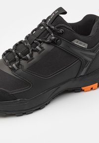 Svart vanntett sneaker med mesh-overdel, forsterket tåhette, reflekterende detaljer, teksturert gummisåle, og oransje såledetaljer.