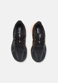 Baskets de course noires avec une tige en tissu en maille, motifs texturés et une semelle rembourrée rose clair. Comprend des lacets noirs et des détails de marque.