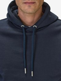 Marinblå bomullshoodie med dragsko på huvan, som har silverfärgade metallöglor och spetsar. Slät textur, minimalistisk design, avslappnad stil.