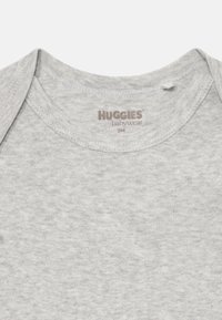 Bodysuit de Huggies en gris claro para bebés de 9 meses con escote tipo sobre, colocado sobre un fondo blanco.