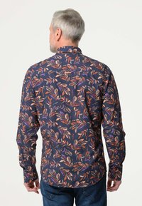 Langarmshirt van marineblauwe stof met een kleurrijk bladerenpatroon in tinten van oranje, paars en beige; voorzien van een standaard kraag en knoopmanchetten.