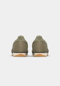 Olive green athletic shoes with a suede-like texture, white mesh panel, and contrasting gum rubber outsole; features Adidas logo on the heel.