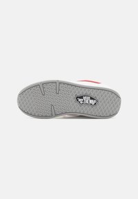 Hvide sneakers med røde detaljer, der har en grå gummisål. Ydersålen har et fiskebensmønster og et logo inden i et skjold.
