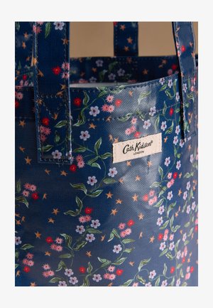 Modrá taška Cath Kidston s kvetinovým a hviezdičkovým vzorom, zelenými listami a bielou štítkom zobrazujúcim názov značky.