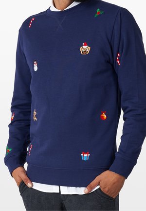 Marineblauer Pullover mit bestickten Weihnachtsmotiven, darunter Zuckerstangen, ein Mops mit Weihnachtsmannmütze, Stechpalmen, Schneemann, Lebkuchenmann, Geschenk und Christbaumkugeln.