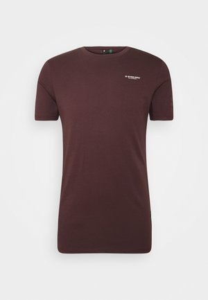 Bordeaux-rotes T-Shirt mit kurzen Ärmeln aus Baumwolle. Mit rundem Halsausschnitt und einem weißen Logo auf der Brust. Glatte Textur, klassischer Schnitt.