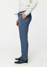 Zachte blauwe sweatpants in een ontspannen pasvorm, met een drawstring tailleband, zijzakken en een textuurstof. Gecombineerd met zwarte sneakers.