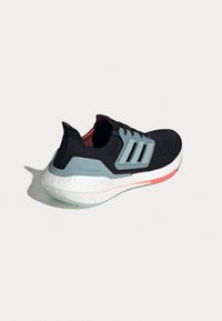 Baskets Adidas Ultraboost noires avec semelle blanche, cage latérale grise et accents rouges subtils, montrées de profil sur un fond uni.