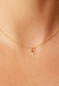 Goldene Halskette mit einem kleinen, minimalistischen Buchstaben "X" Anhänger. Die Kette ist schlank und dünn mit einer feinen Struktur.