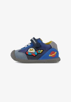 Sneakers per bambini blu e grigi con cinturino in velcro, presentanti un design di un cane in un razzo e accenti colorati di pianeti sui lati.