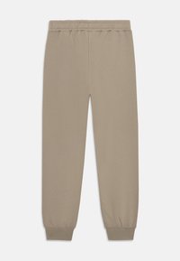 Pantalons de survêtement beige avec une taille élastique, des poignets fuselés et une texture douce et lisse. Design simple, sans motifs ni accents visibles.
