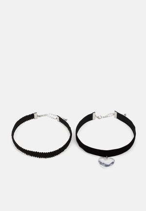 Schwarzes Choker-Set mit einem strukturierten Elastikband und einem glatten Samtband, das mit einem herzförmigen Edelstein-Anhänger verziert ist. Akzente in Silber-Ton.