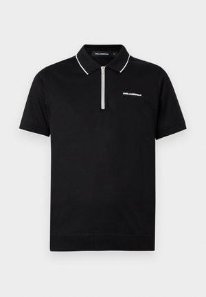 Svart poloskjorte med korte ermer, hvit kant rundt krage og ermer, halvlange glidelås foran, og "KARL LAGERFELD"-logo på brystet.