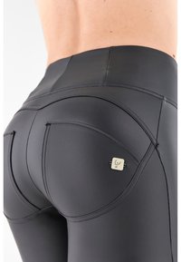Leggings aderenti neri realizzati in un materiale liscio e elasticizzato. Caratterizzati da cuciture curve e da un piccolo tag con il marchio sul retro.