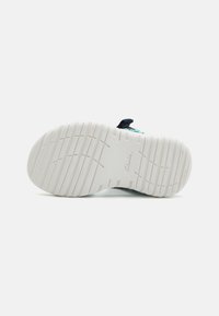 Sula av en sneaker med en texturerad vit gummiyta, som har horisontella och vertikala spår för grepp; inga synliga logotyper.