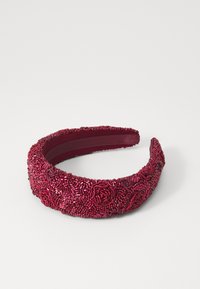 Fascia per capelli rossa con perline, caratterizzata da motivi floreali, fodera interna liscia e design arrotondato. Superficie texturizzata con riflessi lucidi.